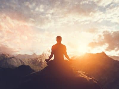 Man in yoga pose, zen meditation at sunset.