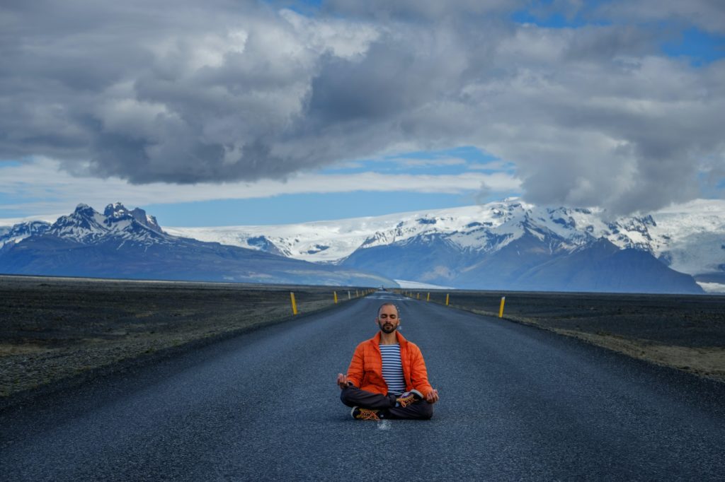 Travel hitchhiker man meditating on a road