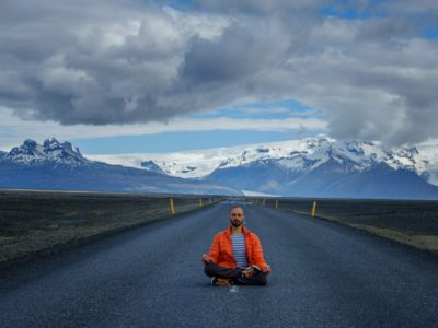 Travel hitchhiker man meditating on a road